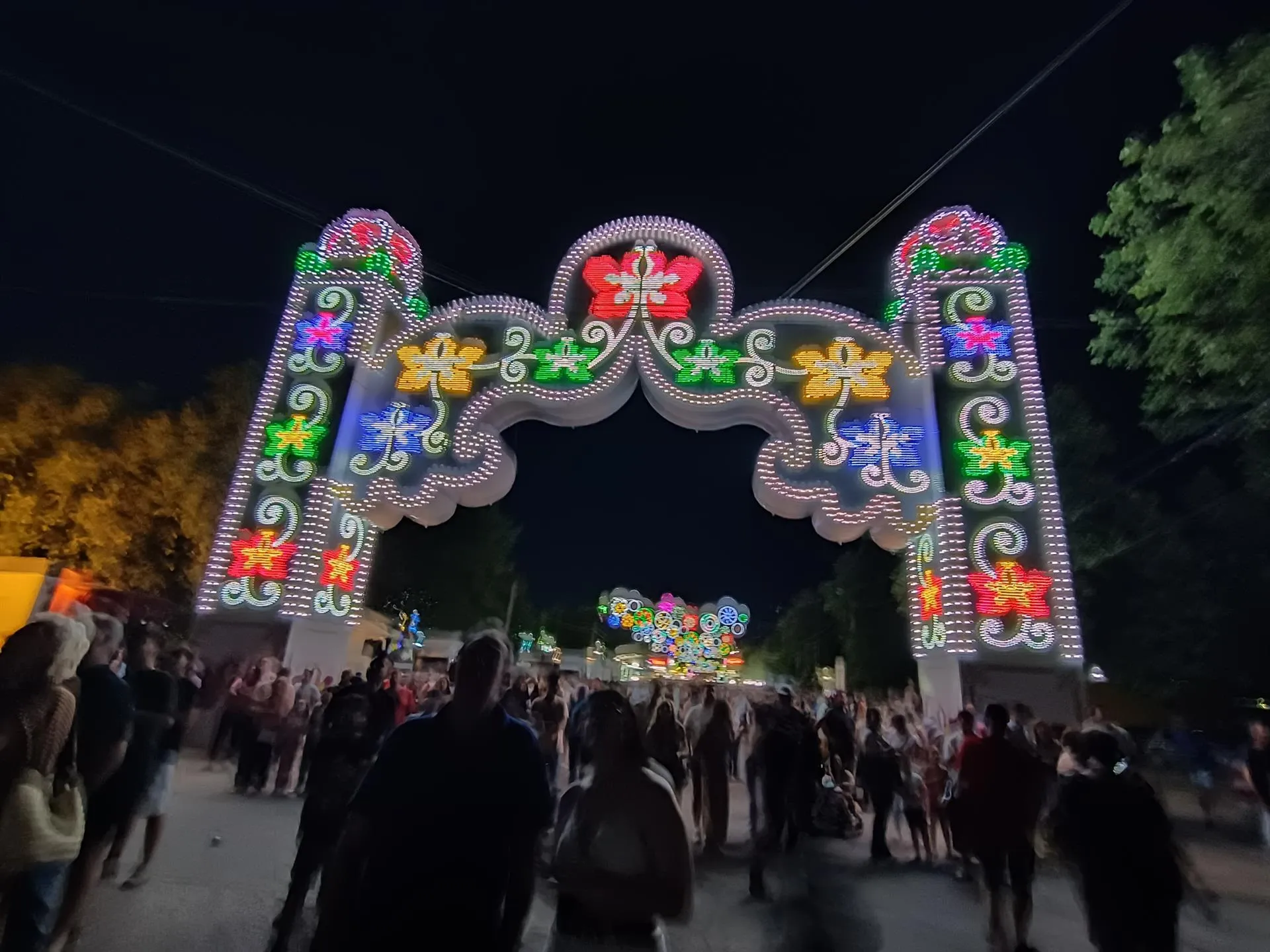 Pórtico iluminado de la Feria de San Fernando en Cáceres lleno de ciudadanos disfrutando la noche